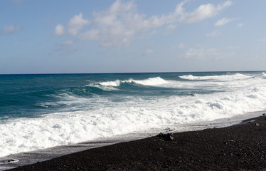Fototapeta na wymiar Rough surf at edge of black sands of Pohoiki beach