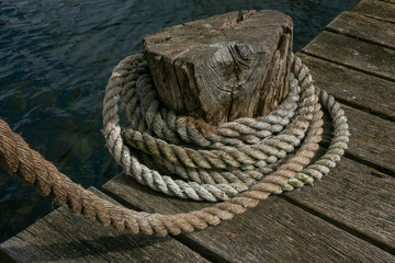Fototapeta na wymiar nautical rope and wooden pier as maritime cordage background