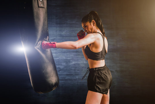 Powerful black woman punching heavy bag during workout  Free Stock Photo