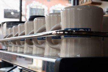 Row of Clean Coffee Mugs Behind a Chrome Rail