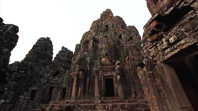 Sliding view from below of impressive high towers of Bayon temple built in the late 12th by khmer civilization and richly decorated. Angkor Wat complex, Cambodia