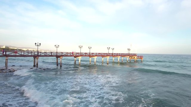 wooden pier in the sea with waves rolling in, romantic at sunset shot filmed in marbella, malaga, spain.
flying drone footage