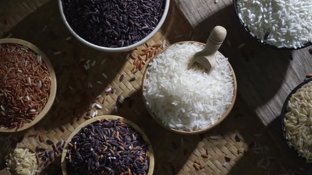 Organic brown rice and asian black riceberry with jasmine white rice in bowl on wooden desk, uncooked products by organic natural food concept, top view