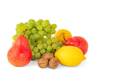 A pair of fragrant yellow lemons with a branch of ripe green grapes and bright scarlet delicious walnuts pears on a white background