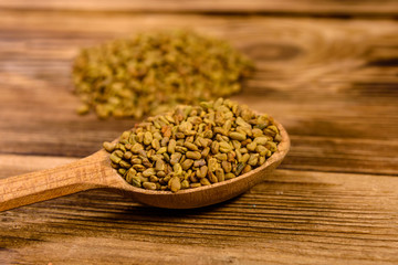 Spoon with fenugreek seeds on wooden table