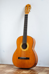 Old sabby guitar leaning on the wall alone standing