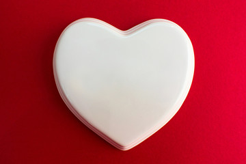  White glossy porcelain heart on a red background; wedding; Wedding card; Love note. Copy space