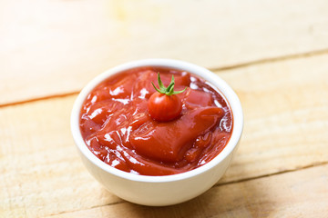 Fresh tomatoes on ketchup in cup tomato sauce on wooden background