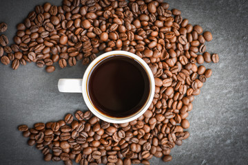 coffee cup on roasted coffee beans on the dark background top view