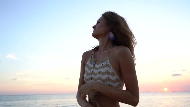 Young beauty girl dansing at tropical beach near sea water at paradise island at sunset, close up. Summer concept. Holiday travel.