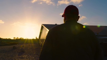 Farmer walking outside in grass and farm in sunshine
