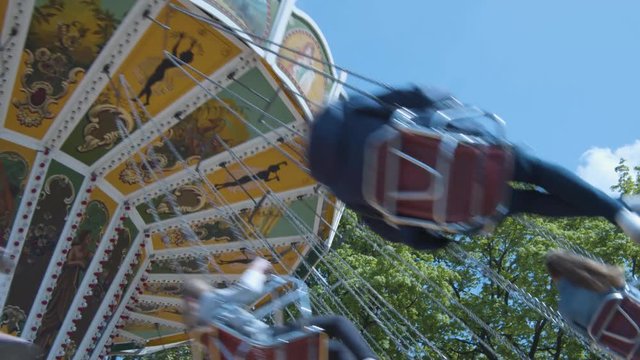 Close Swing carousel rotates in front of blue sky