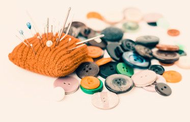 Red knitted needle pad for sewing and sewing buttons on white background with copy space for text.