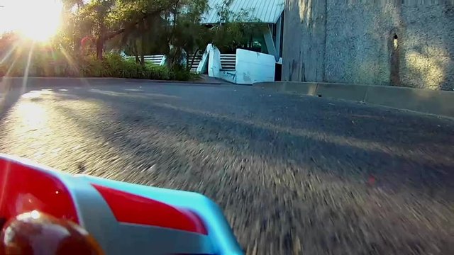 RC Radio control toy car racing on a real asphalt track with sun rays shinning through the natural trees. Real life video game feel.