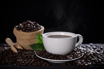 Hot coffee cup with coffee beans on the wooden table
