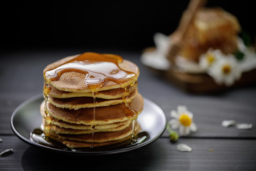 Honey dripping on the stack of pancakes for breakfast on the wooden table, healthy products by...