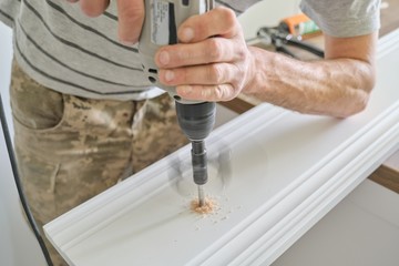 Close-up of carpenters hand using professional woodworking electric tools when working with wood. Male carving hole in wooden panel board, carpentry, woodwork, profession, people