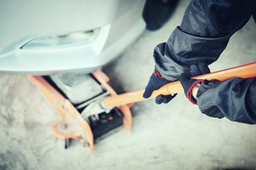 Car care , The car mechanic is lifting the car with the hydraulic Floor Jack. (Spot focus)