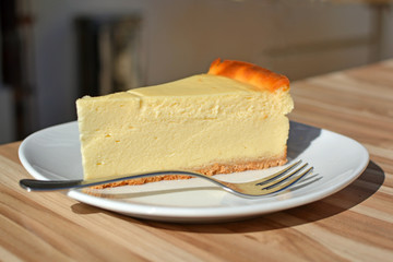 Slice of European Cheesecake on a dessert plate with spoon on table