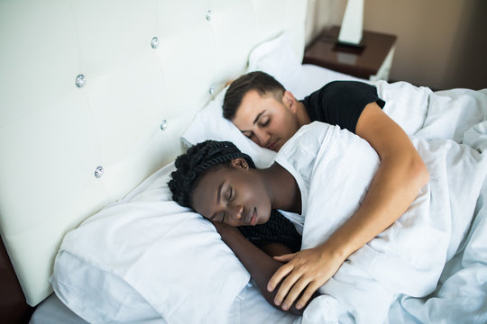 Young cute mixed race couple sleeping together in bed