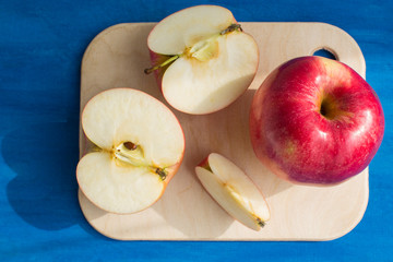  Red apples on a cutting board on blue background