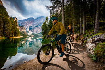 Couple cycling on electric bike, rides mountain trail. Woman and Man riding on bikes in Dolomites...
