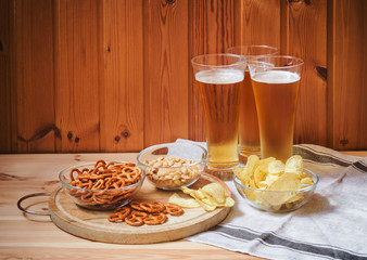 Light  beer with salted pretzels, potato chips and peanuts on  wooden table. Selective focus.