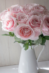 朝日が当たるピンクの薔薇の花束とホーローの花器