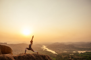Yoga in Hampi temple copyspase at sunset.travel vacation copy spase lady with stylish jumpsuit © yurakrasil
