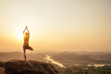 Yoga in Hampi temple copyspase at sunset.travel vacation copy spase lady with stylish jumpsuit