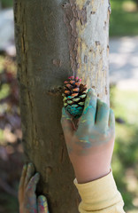 the child paint her hands and hug the tree with finger paint.