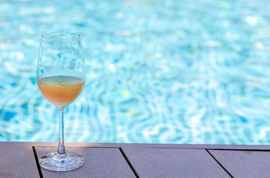A glasses of Rose wine put on swimming pool to celebrate summer season on vacation trip.