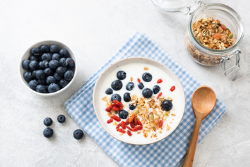 Breakfast yogurt bowl with granola and berries on grey concrete background. Healthy eating, dieting concept. Table top view