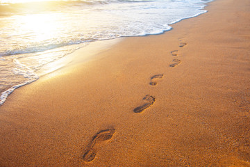 beach, wave and footprints at sunset time
