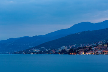 Fototapeta na wymiar Blue evening on the sea, view to the town