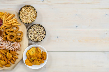 Mix of snacks for beer on light wooden background. Top view, Empty space for text