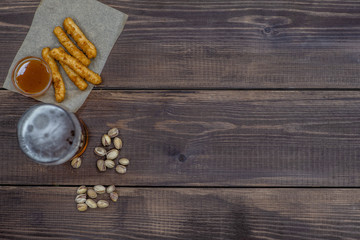 Diverse snacks with beer on dark wooden background. Top view. Empty space for text