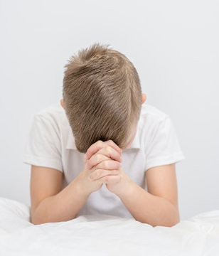 Young boy  praying in bedroom before going to bed