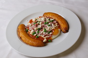 Huevos motuleños is a breakfast food which originated in the town of Motul, Yucatán. The dish is made with eggs on tortillas with black beans, cheese, ham, peas, plantains, and hot sauce.