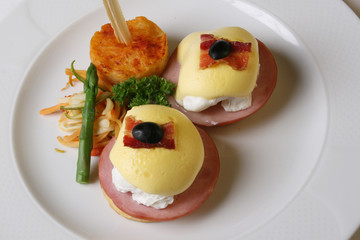 Eggs Benedict is an American breakfast that consists of two halves of an English muffin topped with a poached egg, bacon or ham, and hollandaise sauce. The dish was first popularized in New York City.