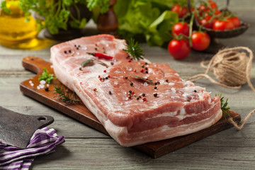 Raw bacon in whole on wooden background.