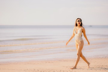 Portrait beautiful young asian woman smile happy walk on the tropical outdoor nature beach sea