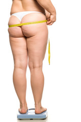 a fat woman stands on a scales and holds a measure her buttocks on white background