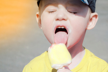 portrait of a child who eat ice cream on a warm summer day. boy in a baseball cap and the sun is shining, close-up face