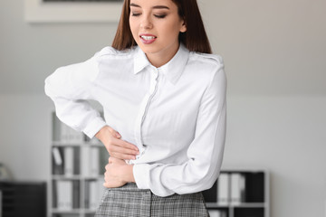 Young woman suffering from abdominal pain in office