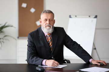 Mature businessman sitting at table in office