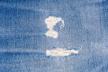Rubbed places on blue jeans with frayed threads close-up