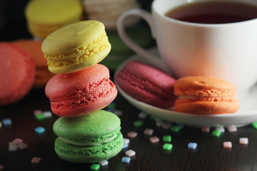 Bright macaroons with a cup of coffee against dark background