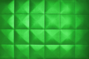 Background consists of large light green squares. Unusual, beautiful and modern background. Rhombic light green color wall of big squares.