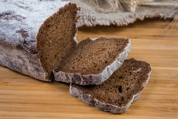 Partly sliced brown bread on wooden surface close-up